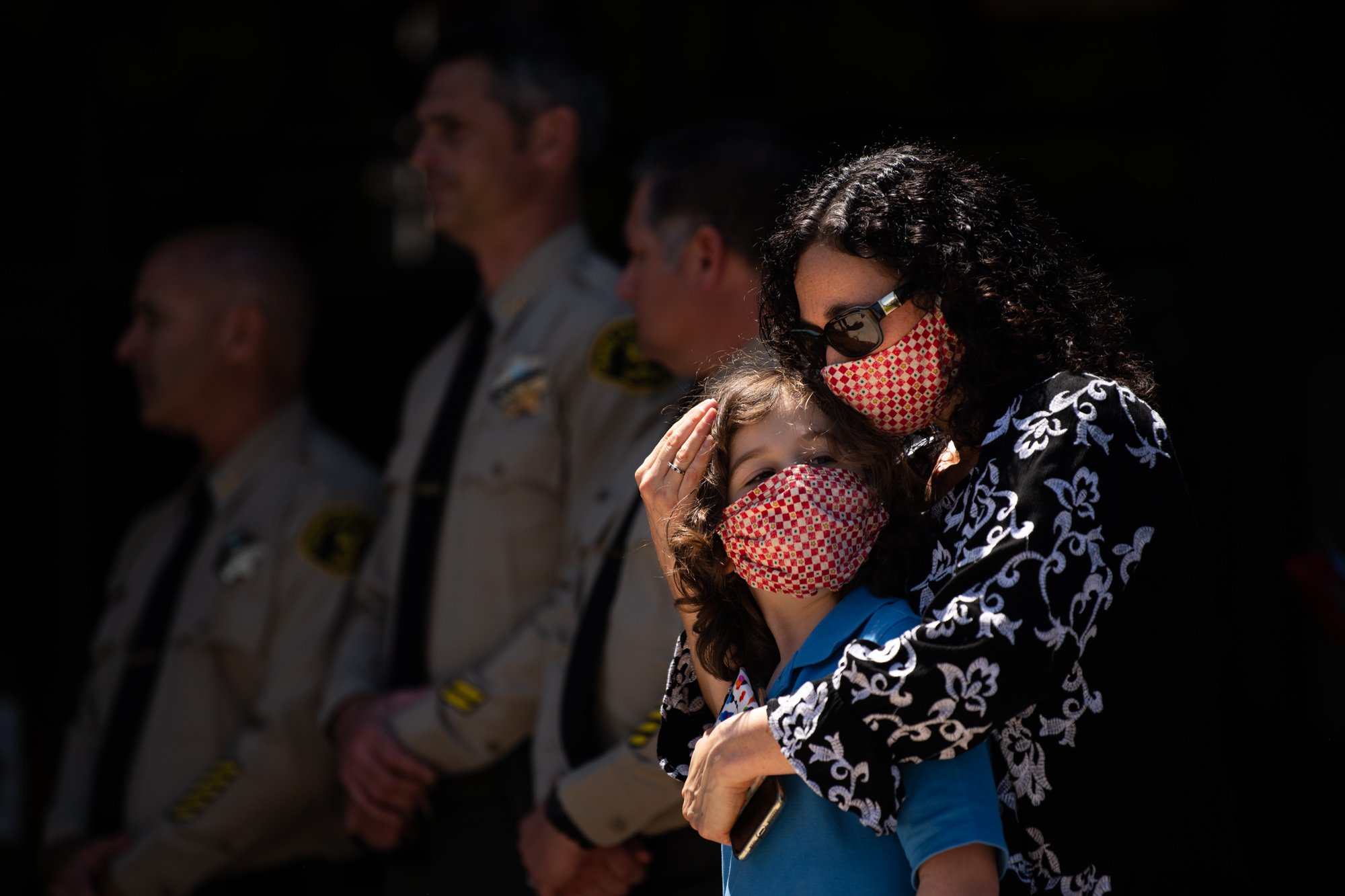 Sheriff Jim Hart's wife, Jackie, consoles their son during the community vigil for the death of Sgt. Damon Gutziller in front of the Santa Cruz County Sheriff's Office on Sunday afternoon. Sgt. Gutziller was killed on Saturday after responding to a call about a suspicious vehicle with guns and bomb making materials.